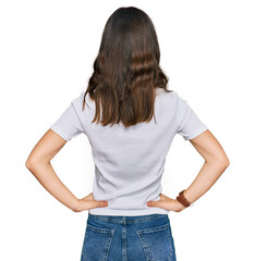 Young beautiful woman wearing casual white t shirt standing backwards looking away with arms on body