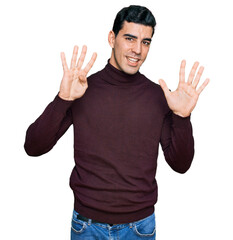 Naklejka premium Handsome hispanic man wearing casual turtleneck sweater showing and pointing up with fingers number nine while smiling confident and happy.