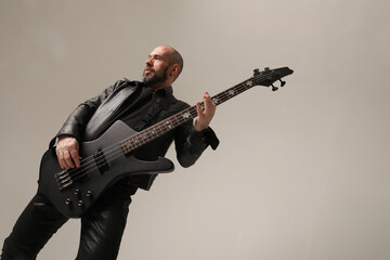 Fototapeta na wymiar Rock musician. A man with shaved head poses at the studio in black clothes. 