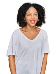 Young african american girl wearing casual clothes winking looking at the camera with sexy expression, cheerful and happy face.