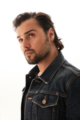 Handsome bearded young man wearing denim jacket posing on the white background.