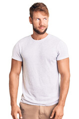 Fototapeta premium Young caucasian man wearing casual white tshirt smiling looking to the side and staring away thinking.