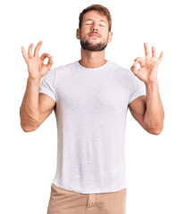 Young caucasian man wearing casual white tshirt relax and smiling with eyes closed doing meditation gesture with fingers. yoga concept.