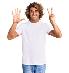 Young hispanic man wearing casual white tshirt showing and pointing up with fingers number seven while smiling confident and happy.