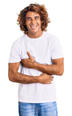 Young hispanic man wearing casual white tshirt smiling and laughing hard out loud because funny crazy joke with hands on body.