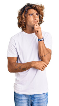 Young hispanic man wearing casual white tshirt thinking worried about a question, concerned and nervous with hand on chin
