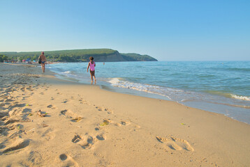 Sandy beach and sea, people walk and swim in the sea