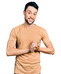 Obraz premium Hispanic man with beard wearing casual t shirt with hands together and crossed fingers smiling relaxed and cheerful. success and optimistic