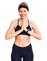 Fototapeta premium Young beautiful blonde woman wearing sportswear praying with hands together asking for forgiveness smiling confident.