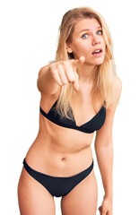 Young beautiful blonde woman wearing bikini pointing displeased and frustrated to the camera, angry...