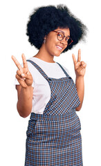 Young african american girl wearing casual clothes smiling looking to the camera showing fingers doing victory sign. number two.