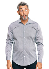 Middle age grey-haired man wearing casual clothes making fish face with lips, crazy and comical gesture. funny expression.