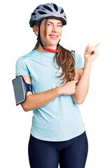 Beautiful caucasian young woman wearing bike helmet smiling happy pointing with hand and finger to the side