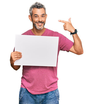 Middle age grey-haired man holding blank empty banner pointing finger to one self smiling happy and proud