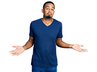 Young african american man wearing casual t shirt clueless and confused expression with arms and...