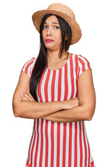 Young hispanic woman wearing summer hat skeptic and nervous, disapproving expression on face with crossed arms. negative person.