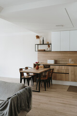 Modern new apartment interior design. White furniture with utensils, shelves, dinning table, chairs. Apartments for rent