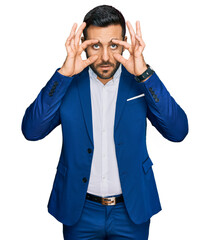 Young hispanic man wearing business jacket trying to open eyes with fingers, sleepy and tired for...