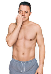 Fototapeta premium Handsome young man wearing swimwear shirtless looking stressed and nervous with hands on mouth biting nails. anxiety problem.
