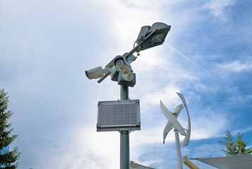 Wind generator, solar panel on a lamppost with video surveillance cameras in an urban environment. Green energy