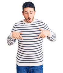 Young hispanic man wearing casual clothes pointing down with fingers showing advertisement, surprised face and open mouth