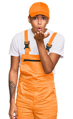 Young handsome african american man wearing handyman uniform looking at the camera blowing a kiss with hand on air being lovely and sexy. love expression.