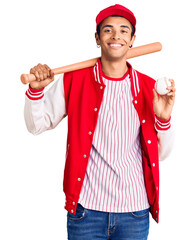 Young african amercian man playing baseball holding bat and ball looking positive and happy standing and smiling with a confident smile showing teeth