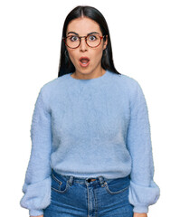 Young hispanic woman wearing casual clothes and glasses afraid and shocked with surprise...