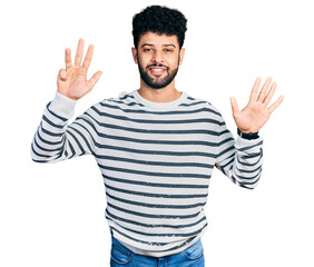 Young arab man with beard wearing casual striped sweater showing and pointing up with fingers number nine while smiling confident and happy.