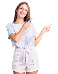 Young beautiful blonde woman wearing tye die tshirt smiling and looking at the camera pointing with...