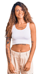 Young hispanic woman with tattoo wearing casual clothes looking positive and happy standing and smiling with a confident smile showing teeth