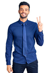 Young handsome hispanic man wearing business clothes smiling with happy face winking at the camera...