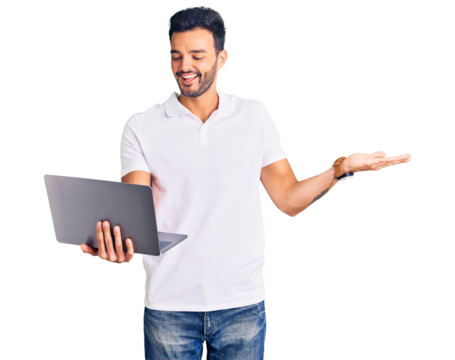 Young handsome hispanic man working using computer laptop celebrating victory with happy smile and winner expression with raised hands