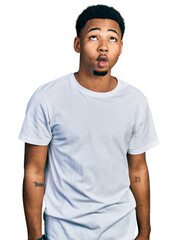 Young african american man wearing casual white t shirt making fish face with lips, crazy and comical gesture. funny expression.