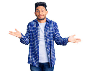 Handsome latin american young man wearing casual shirt clueless and confused expression with arms...