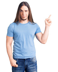 Young adult man with long hair wearing casual clothes smiling happy pointing with hand and finger to the side