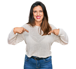 Beautiful hispanic woman wearing casual sweater looking confident with smile on face, pointing oneself with fingers proud and happy.