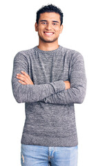 Hispanic handsome young man wearing casual sweater happy face smiling with crossed arms looking at...