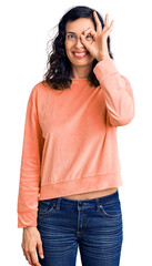 Fototapeta premium Young beautiful hispanic woman wearing casual clothes doing ok gesture with hand smiling, eye looking through fingers with happy face.