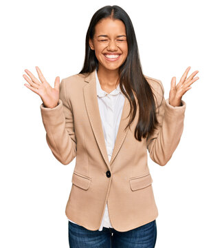 Beautiful hispanic woman wearing business jacket celebrating mad and crazy for success with arms raised and closed eyes screaming excited. winner concept