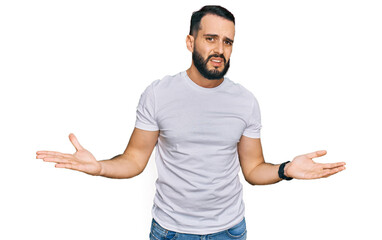 Young man with beard wearing casual white t shirt clueless and confused with open arms, no idea...