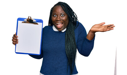 Young black woman with braids holding clipboard with blank space celebrating victory with happy...