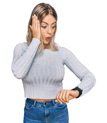 Fototapeta premium Beautiful blonde woman wearing casual clothes looking at the watch time worried, afraid of getting late
