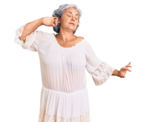 Senior woman with gray hair wearing bohemian style stretching back, tired and relaxed, sleepy and yawning for early morning