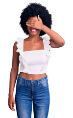Young african american woman wearing casual clothes smiling and laughing with hand on face covering eyes for surprise. blind concept.