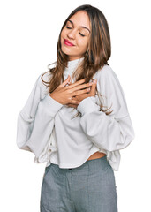 Young brunette woman wearing casual turtleneck sweater smiling with hands on chest with closed eyes and grateful gesture on face. health concept.