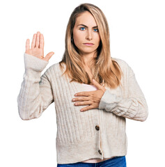 Young blonde woman wearing casual clothes swearing with hand on chest and open palm, making a...