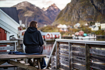 young woman drinking coffee in the morning and taking a look on the bay in Sørvågen fisherman...