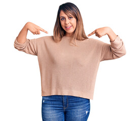 Young beautiful woman wearing casual sweater looking confident with smile on face, pointing oneself...