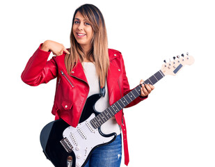 Fototapeta premium Young beautiful woman playing electric guitar pointing finger to one self smiling happy and proud